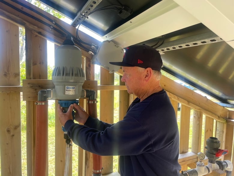 A man adjusts a device inside a wooden building 