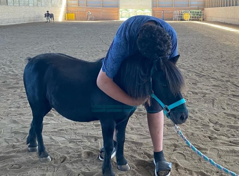 A picture of a boy hugging a pony as a part of the Equine Assisted Therapy sessions. 