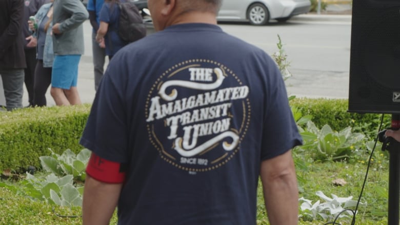 A man with his back to the camera has a T-shirt that reads 'Amalgamated Transit Union'.