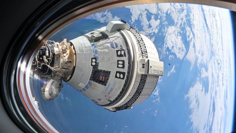 A view from a window that shows a gumdrop-shaped white spacecraft over Earth.