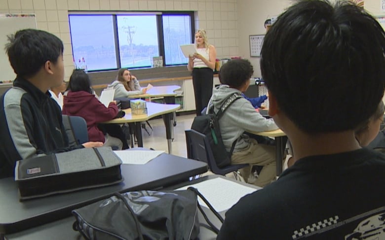 A teacher stands at the head of a classroom