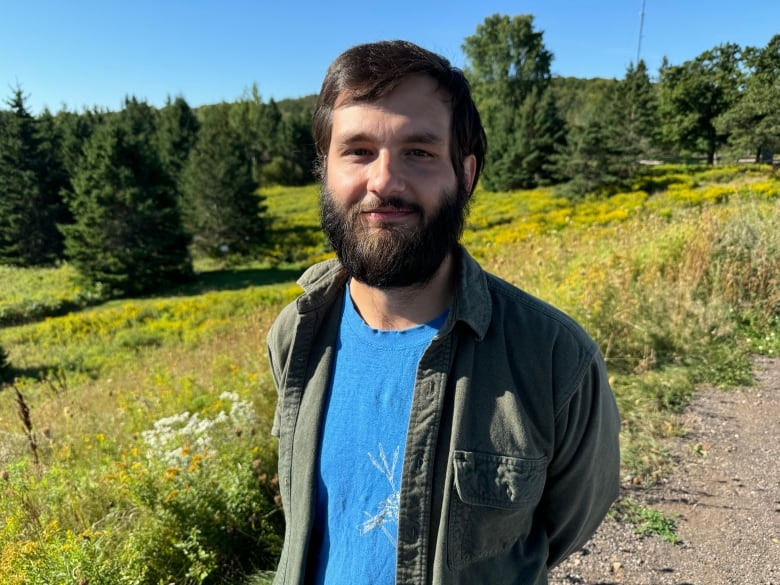 A man stands in front of trees.