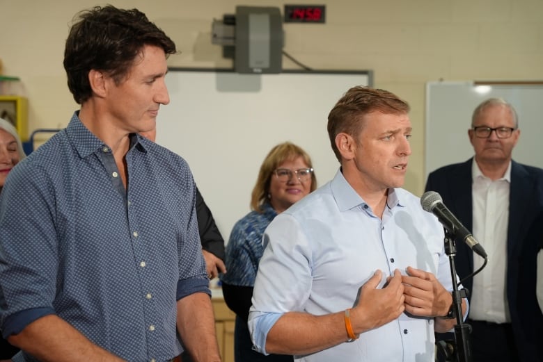 Two men stand side by side at a microphone.