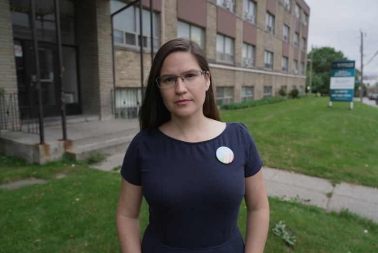 Woman standing infront of low-rise apartment building.