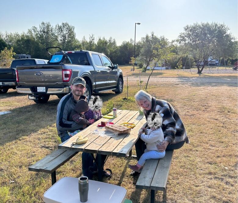 Starla Schneider sits at a picnic table with her son and grandkids.