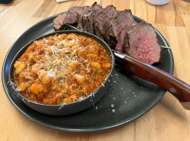 A pot of a red creamy looking dish sits next to sliced meat.