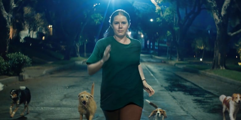 Amy Adams runs at night in the middle of the street.