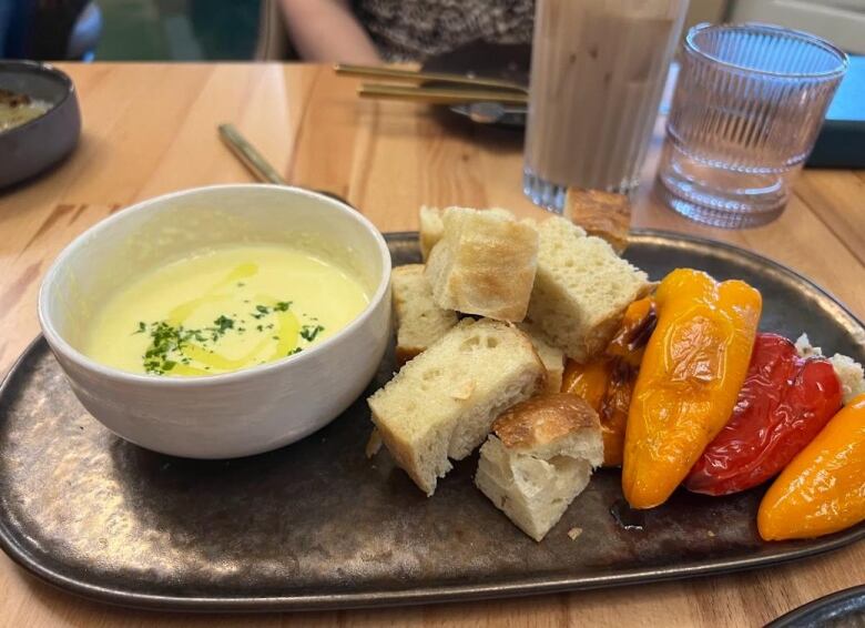 A plate shows peppers, bread and a bowl of soup. 