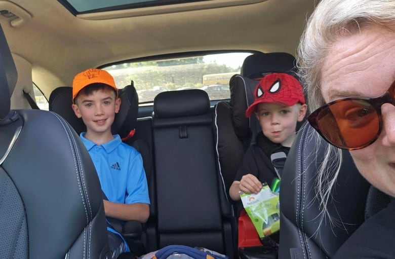 A selfie of a woman in a car  with two boys in the back seat