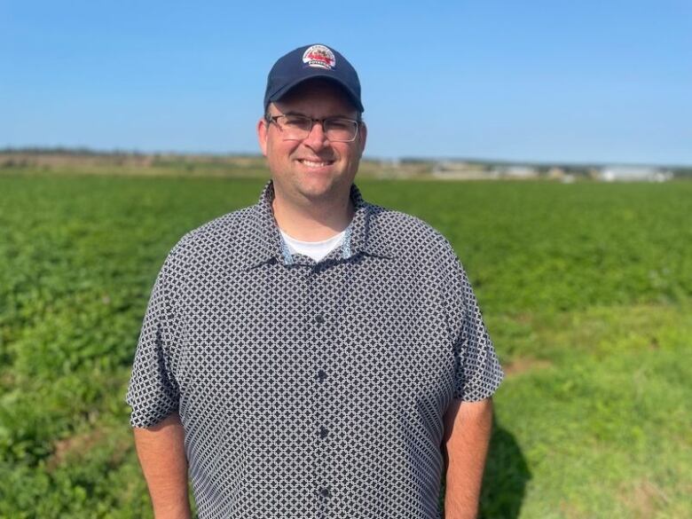 A man in a ballcap next to a potato field 