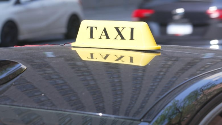 A yellow taxi sign sitting on top of a car. 