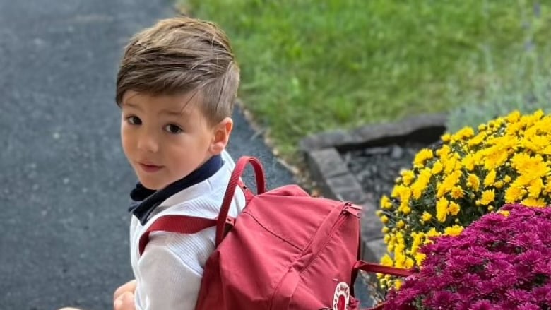 A small boy in a backpack sitting on a step