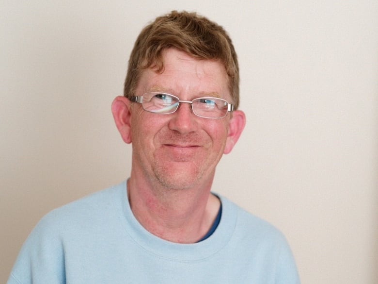 Picture of a man wearing a pair of eyeglasses smiling to the camera.