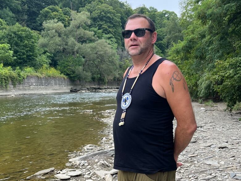 Alan Colley stands on the rocky shore of the Humber River. 