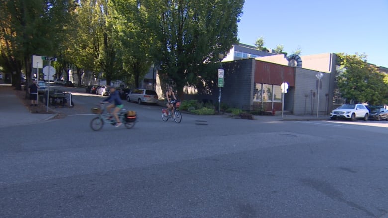 Two bicycles travel past each other, going different directions through an intersection.