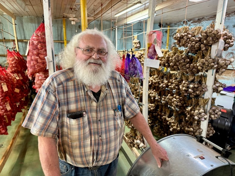 Al Picketts stands in front of drying garlic.