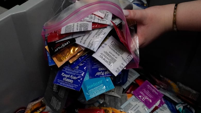 A sexual health peer educator dumps condoms into a container on campus.