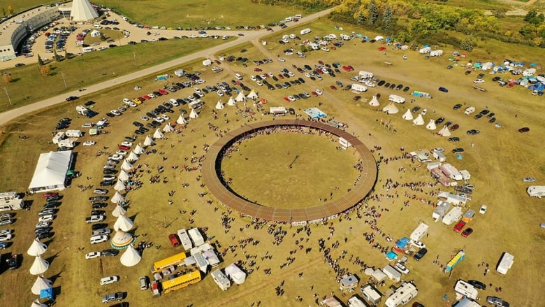 A scene from the sky looks at a powwow arbor with tipis surrounding it.