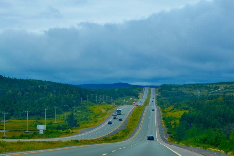 The highway is large and empty with just a couple cars dotting the distance. 