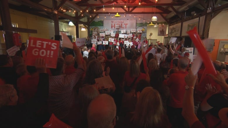 A room of people waving signs and cheering. 