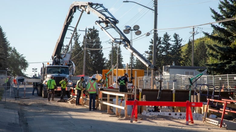 Construction workers watch as concrete is poured into a hole where a water pipe is being repaired.