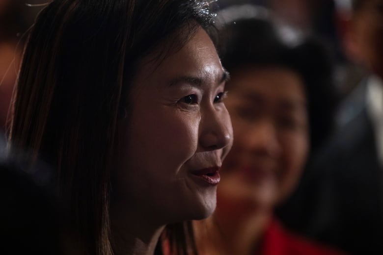 An East Asian woman smiles as she is pictured in profile.