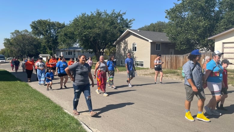 A group of people walk down a road.