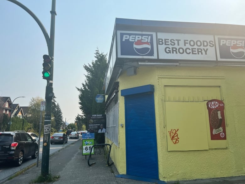 A yellow convenience store in Vancouver with a blue door.