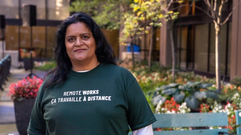 A union executive at an outdoor rally in summer. Her shirt says 'Remote works.'