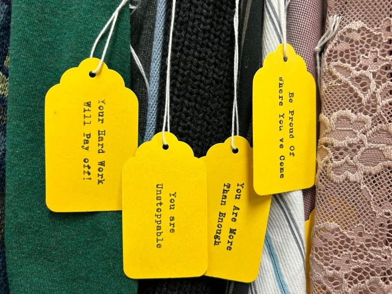 Four yellow tags hang on clothing pieces.  The one on the far left says 