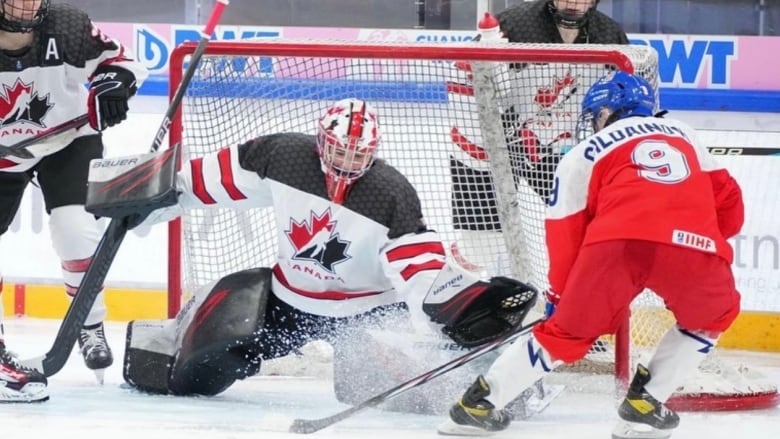 A hockey goalkeeper is seen defending the net as a player tries to score a goal.