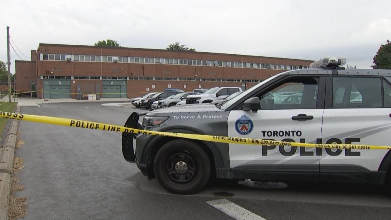 Police car outside a school in a parking lot cordoned off with police tape