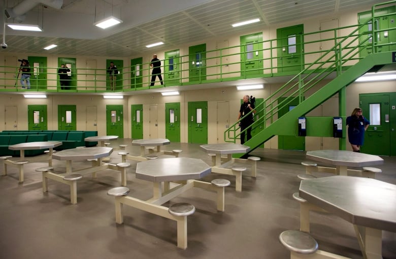 The inside of jail, with green doors and tables seen in the foreground