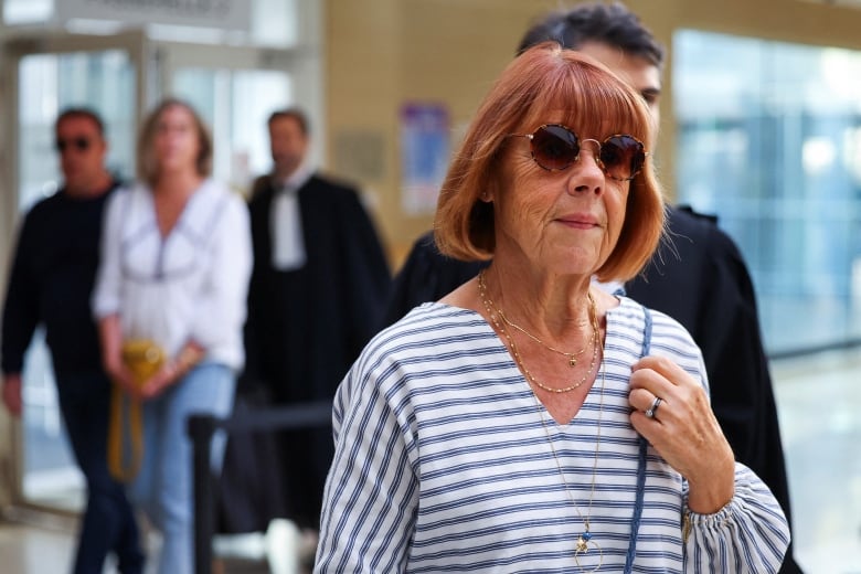 An older woman  in sunglasses walks into a court