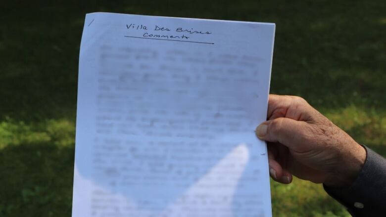 A man holds pages of handwritten notes 