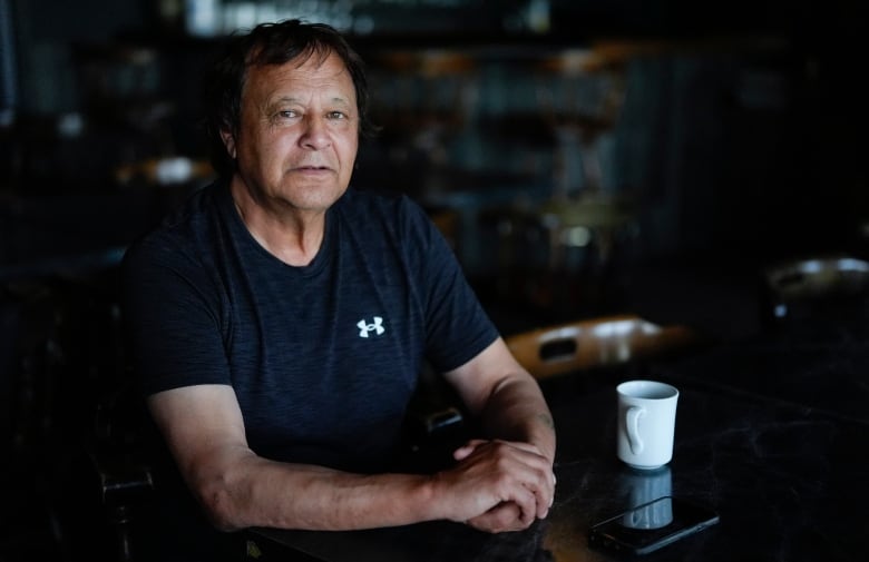 A man sits at a table with his forearms on the table top