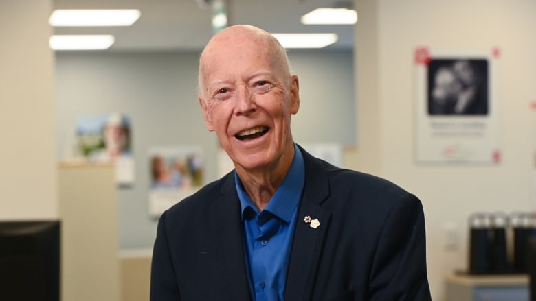 man in navy blazer and blue shirt smiles.