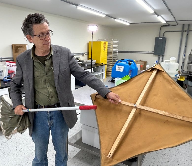 A man holding a net and an insect collecting canvas.