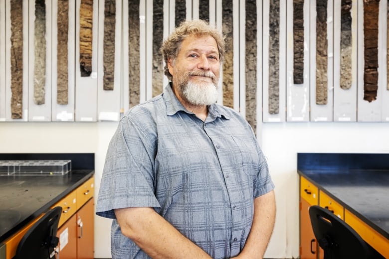 A man with a beard in a button-up T-shirt smiles at the camera.