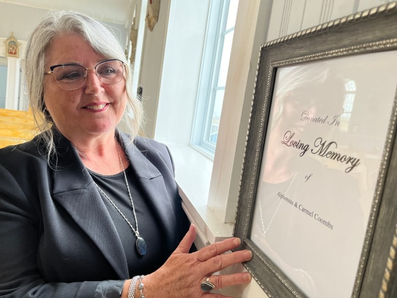 A woman standing next to a picture frame with 