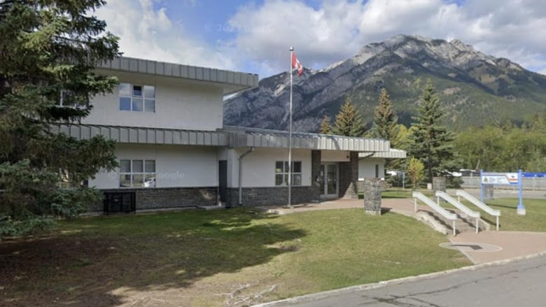 A building surrounded by mountains with an RCMP billboard out front. 