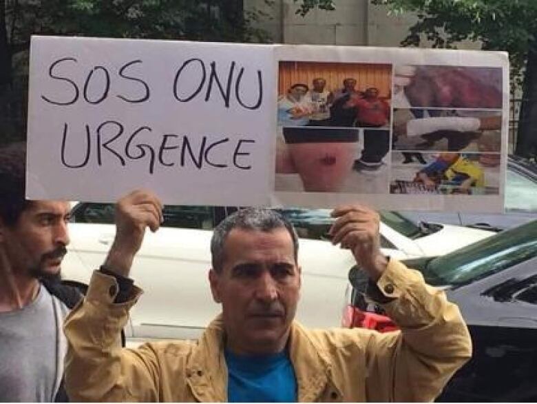 Portrait of a man holding up a protest placard