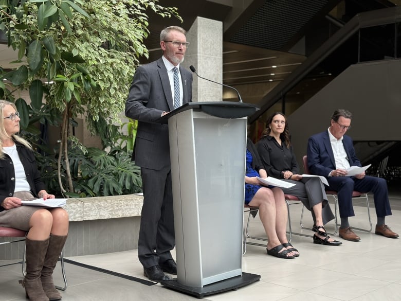 A man in a suit stands behind a podium. 