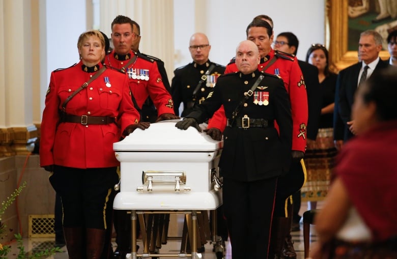 A group of people escort a casket. 