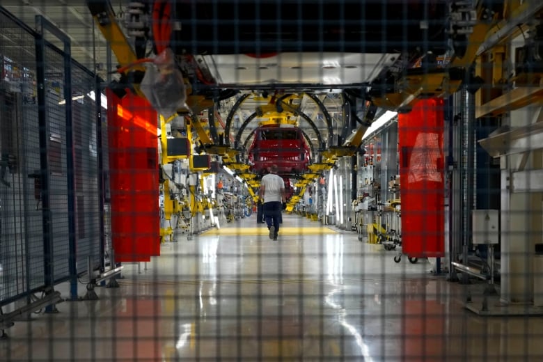 A Serbian factory worker walks by all-new Fiat Grande Panda cars in the assembly hall in the Stellantis factory, in Kragujevac, some 100 kilometers (70 miles) south of Belgrade, Serbia, Monday, July 22, 2024. (AP Photo/Darko Vojinovic)