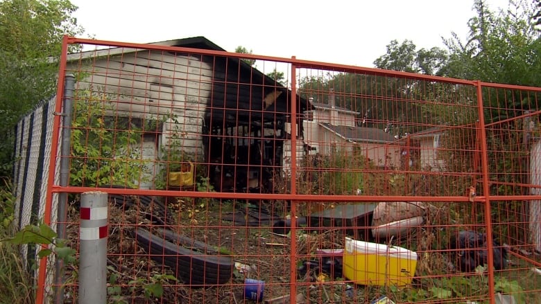 A charred garage in a fenced off property with detritus strewn across the yard. 