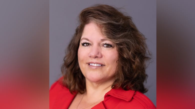 Woman with a red blazer stares at the camera smiling 