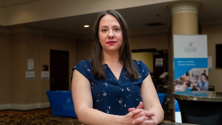 A woman in a blue shirt sits at a table in an office building.