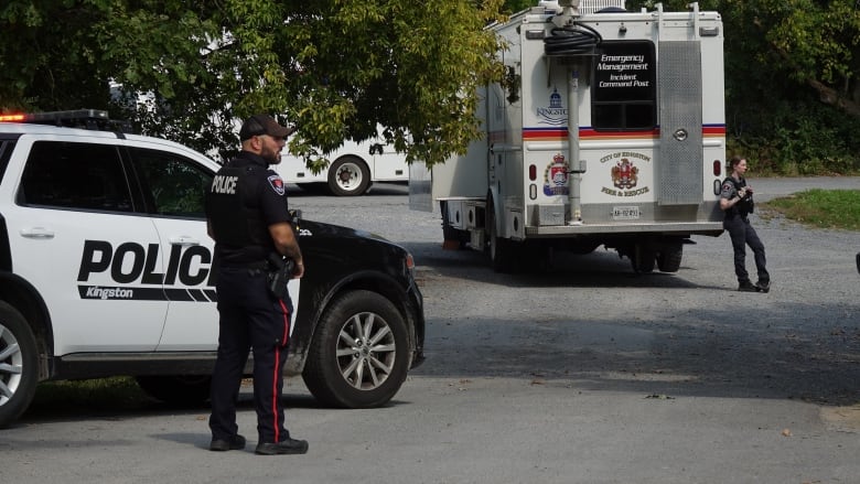 Police cruiser and ambulance parked near each other. Two officers stand near the vehicles. 