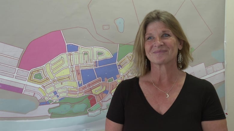 A woman stands in front of a map.